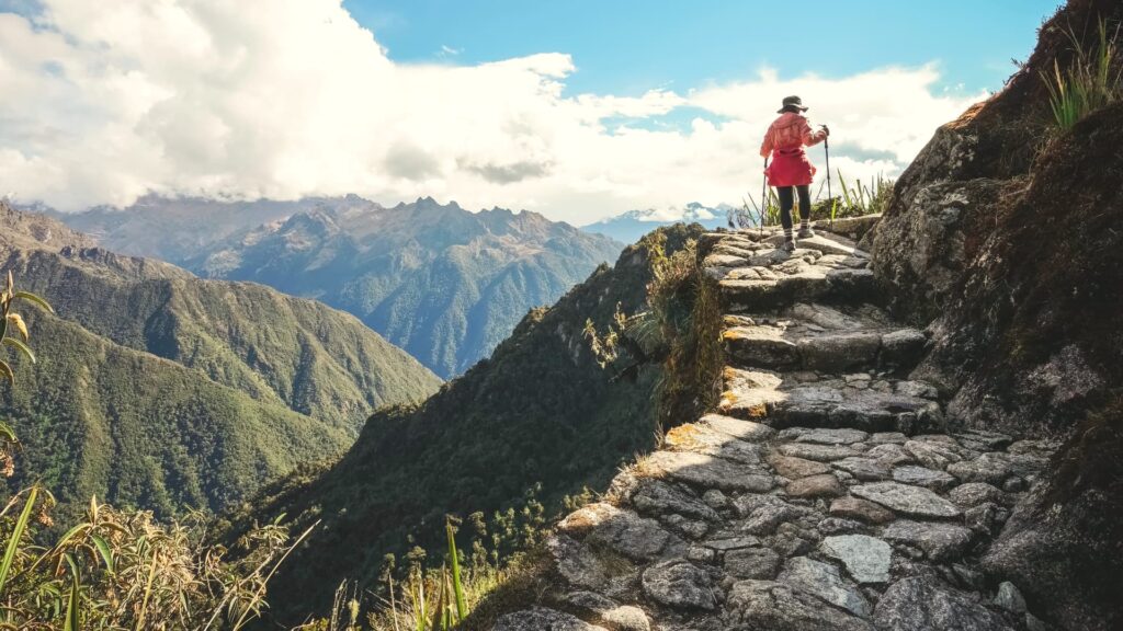 Trekking en Cusco - Senderistas caminando por un sendero empedrado del Camino Inca con vista a las montañas.