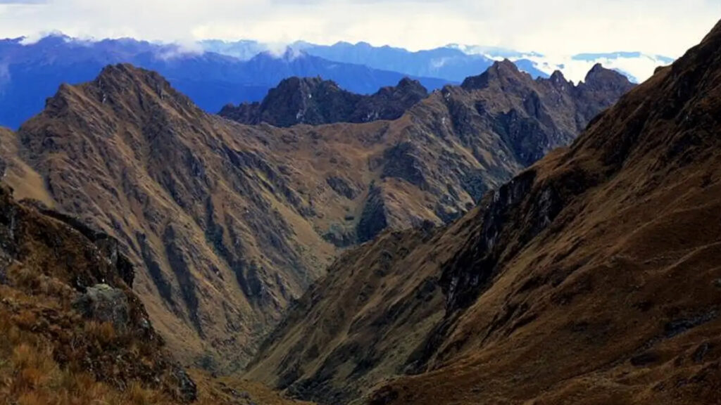 Hikers climbing the steep trail to Warmiwañusca Pass with majestic mountain peaks in the background