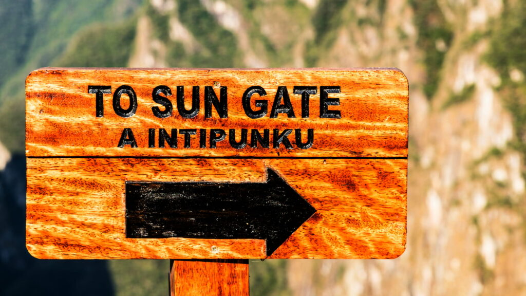 Panoramic view of Machu Picchu from the Sun Gate in Cusco, with the Inca ruins and surrounding mountains at sunrise.