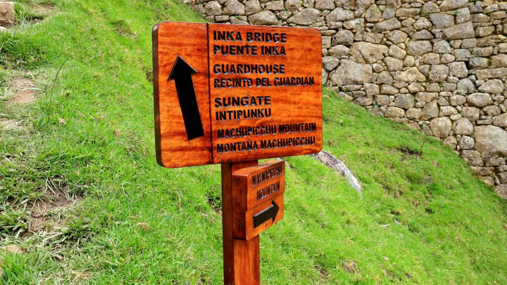 A traveler at the Sun Gate in Machu Picchu, Cusco, overlooking the ancient Inca citadel and the soaring Andean peaks under a clear sky.