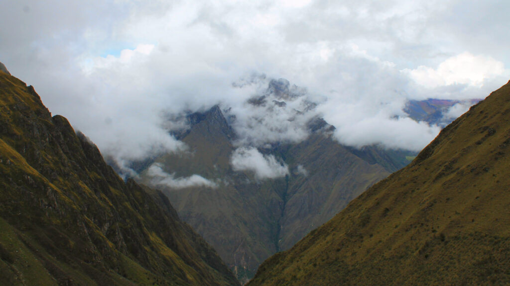 Hikers ascending Warmiwañusca Pass surrounded by rugged mountains and clear skies on the Inca Trail